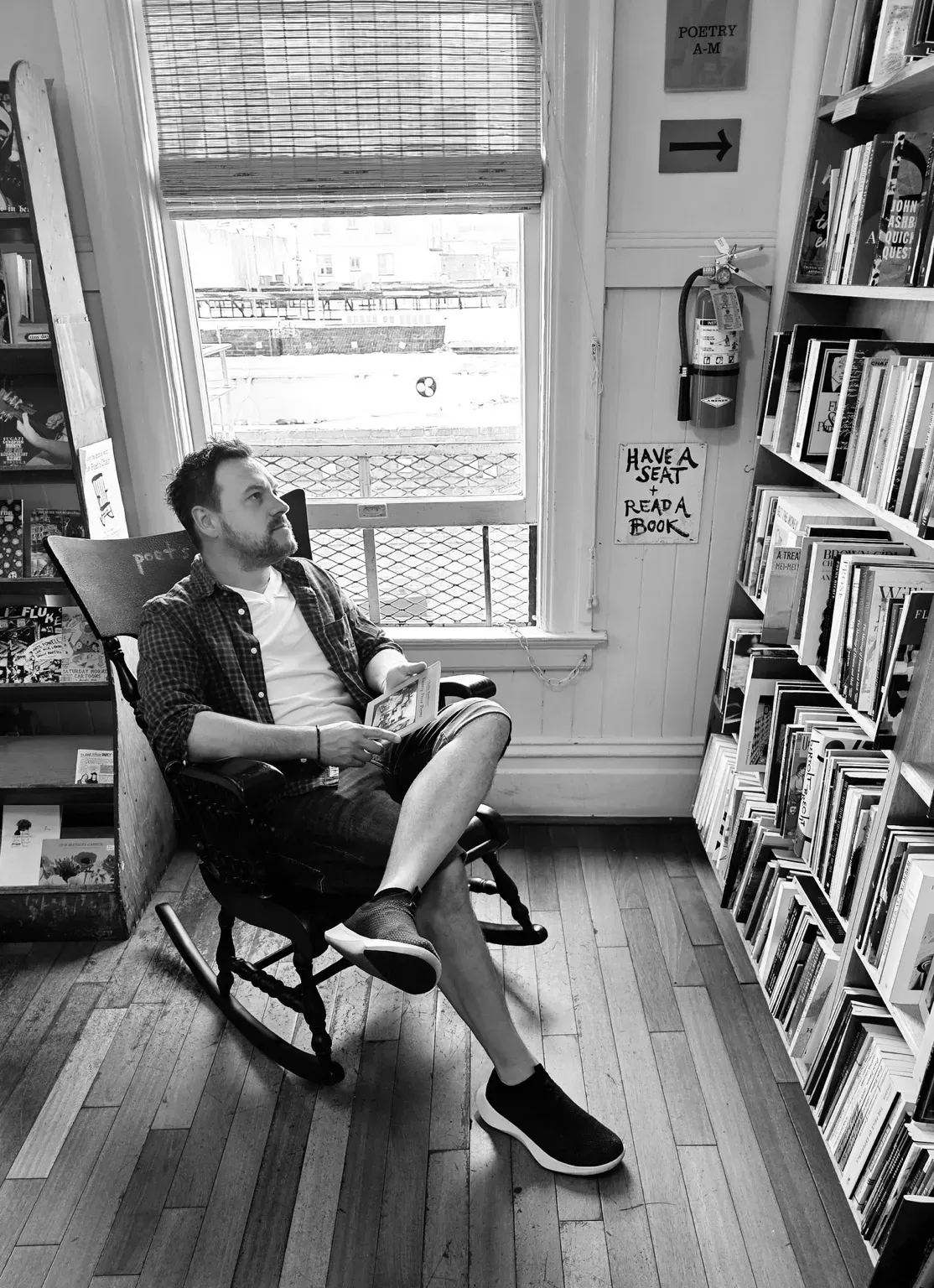 The author sat in a rocking chair and staring a bookshelf at City Lights Bookstore in San Franciso, California.