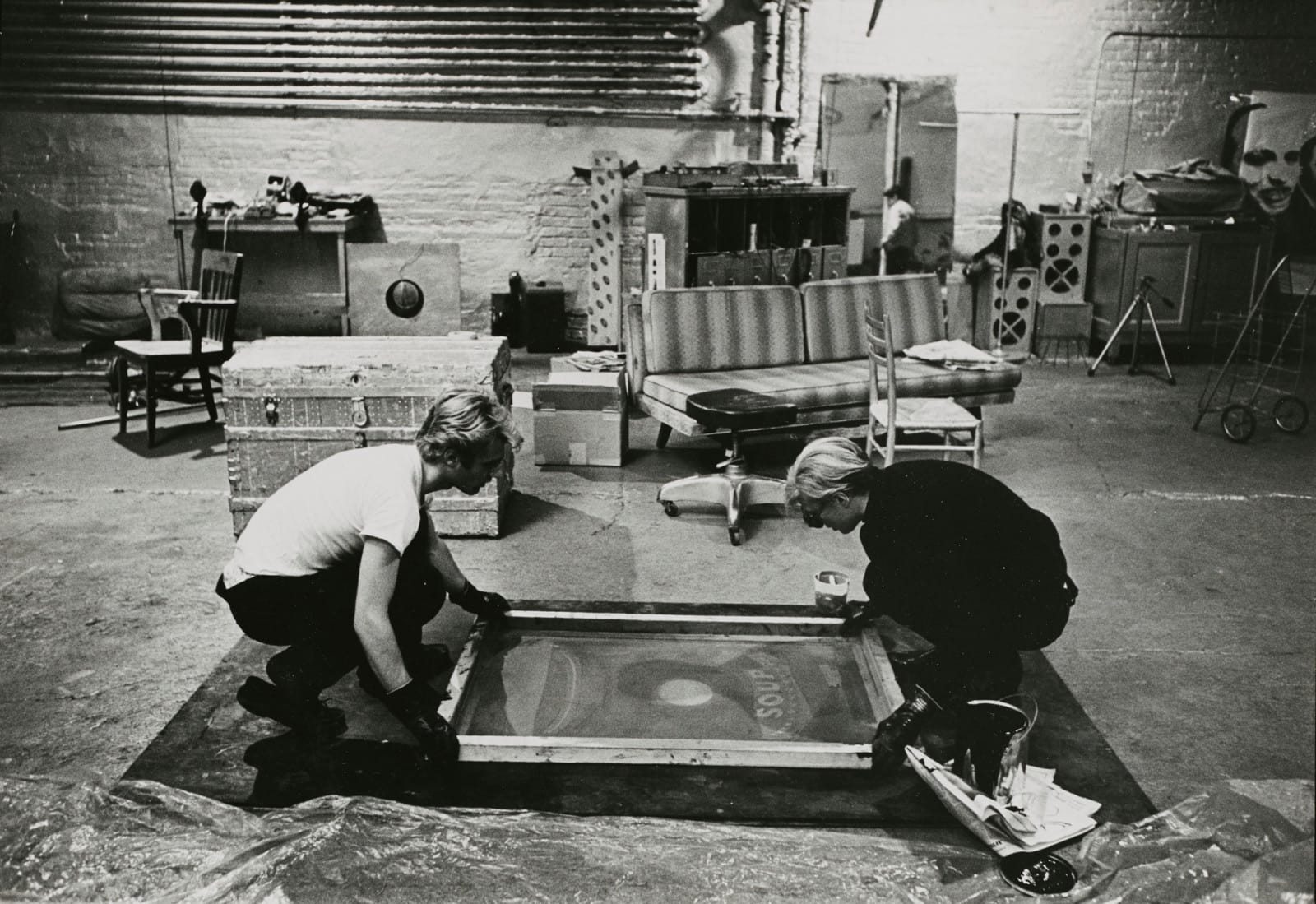 Andy Warhol and Gerard Malanga working on a silkscreen print together at The Factory