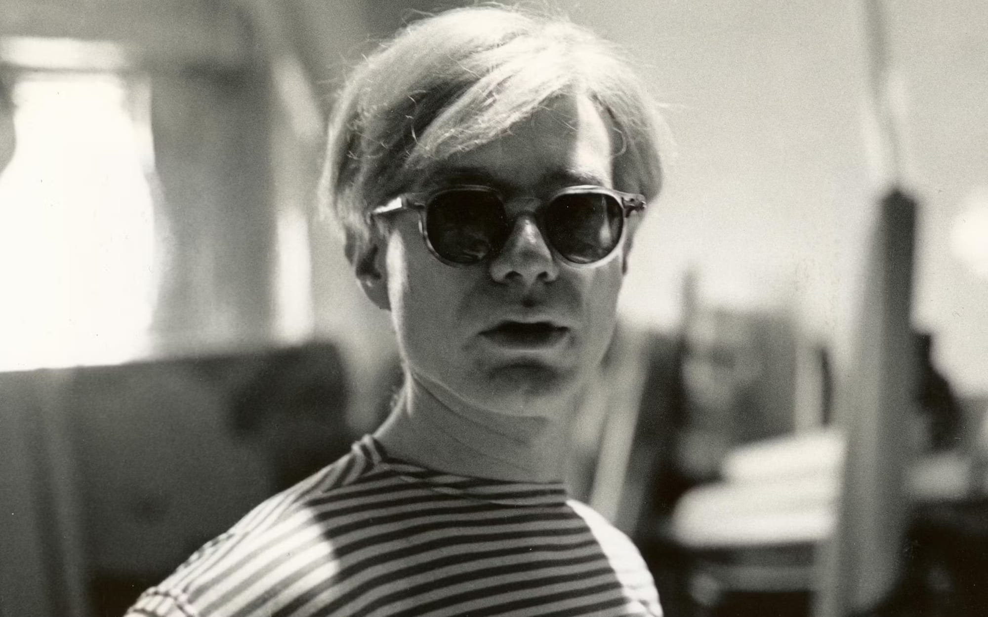 Andy Warhol wearing sunglasses and looking directly at the camera